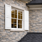 Home exterior white panel window shutters and / or door shutters on a brick home.